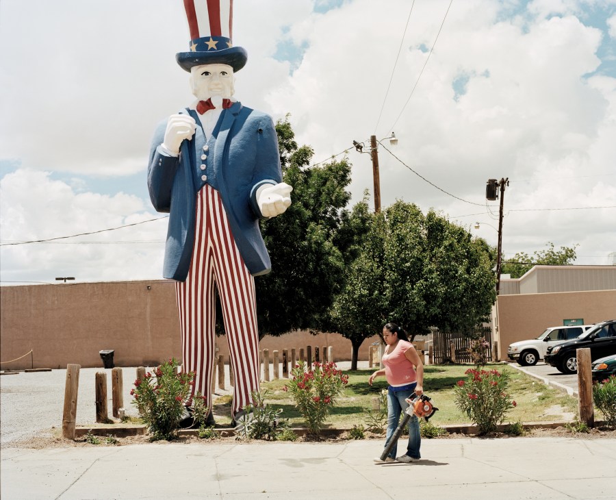 A large Uncle Sam statue looms over a Hispanic woman standing in front of it in New Mexico.