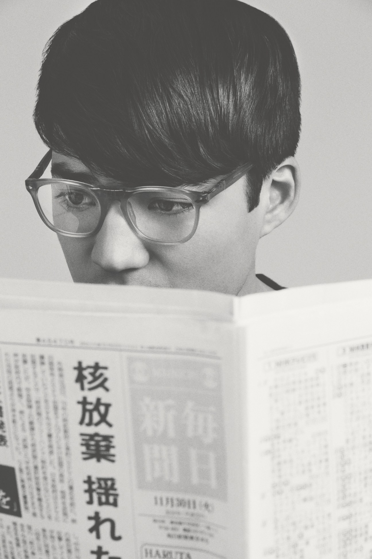 Person wearing Persol 2996-V glasses reading a Japanese newspaper in black and white.