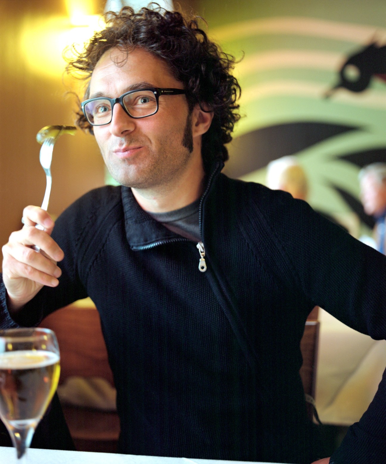 Aki Arjola holding a pickle while wearing glasses and a dark sweater