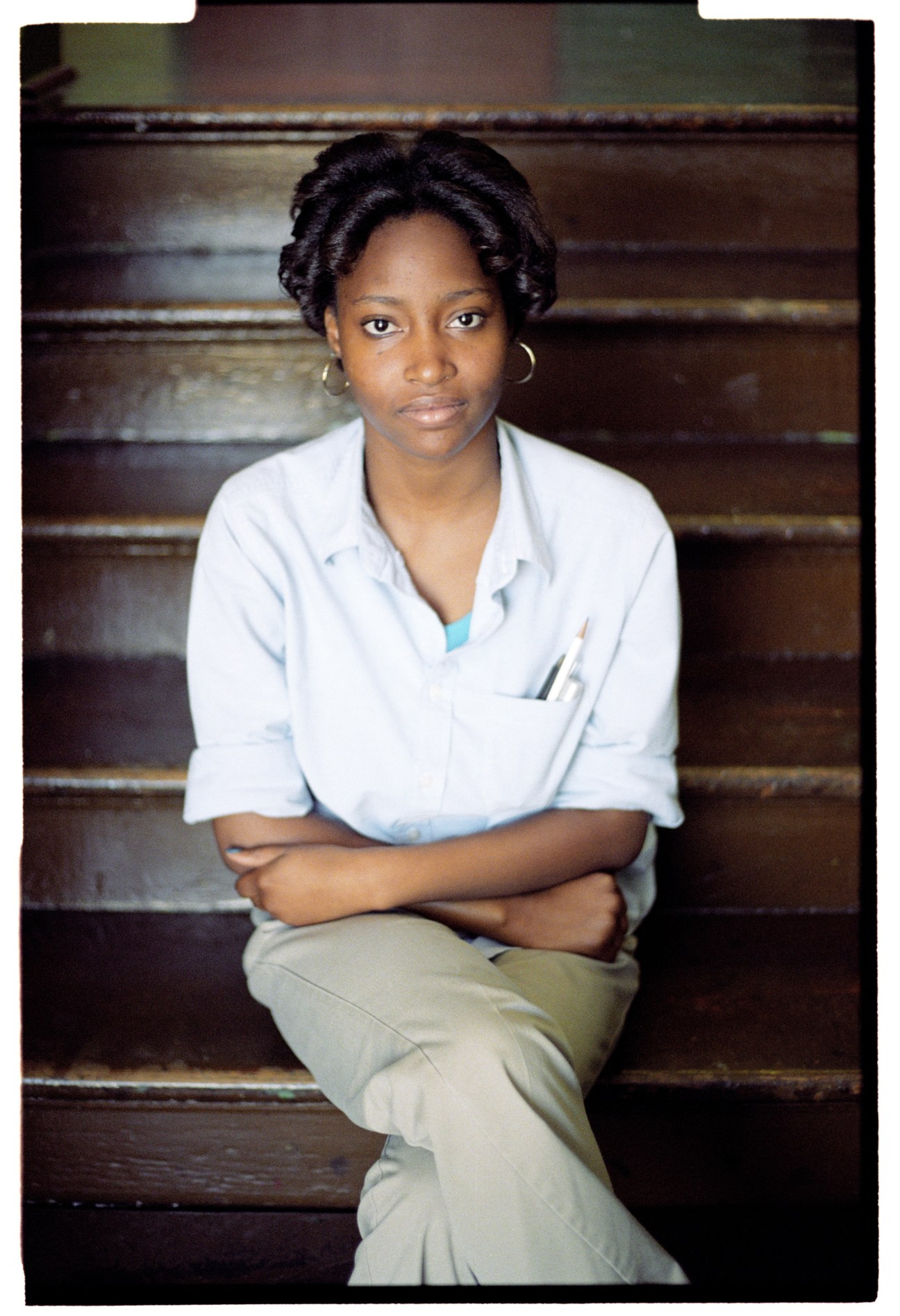 International High School student Tessa Joseph sits on wooden steps wearing a light blue shirt.