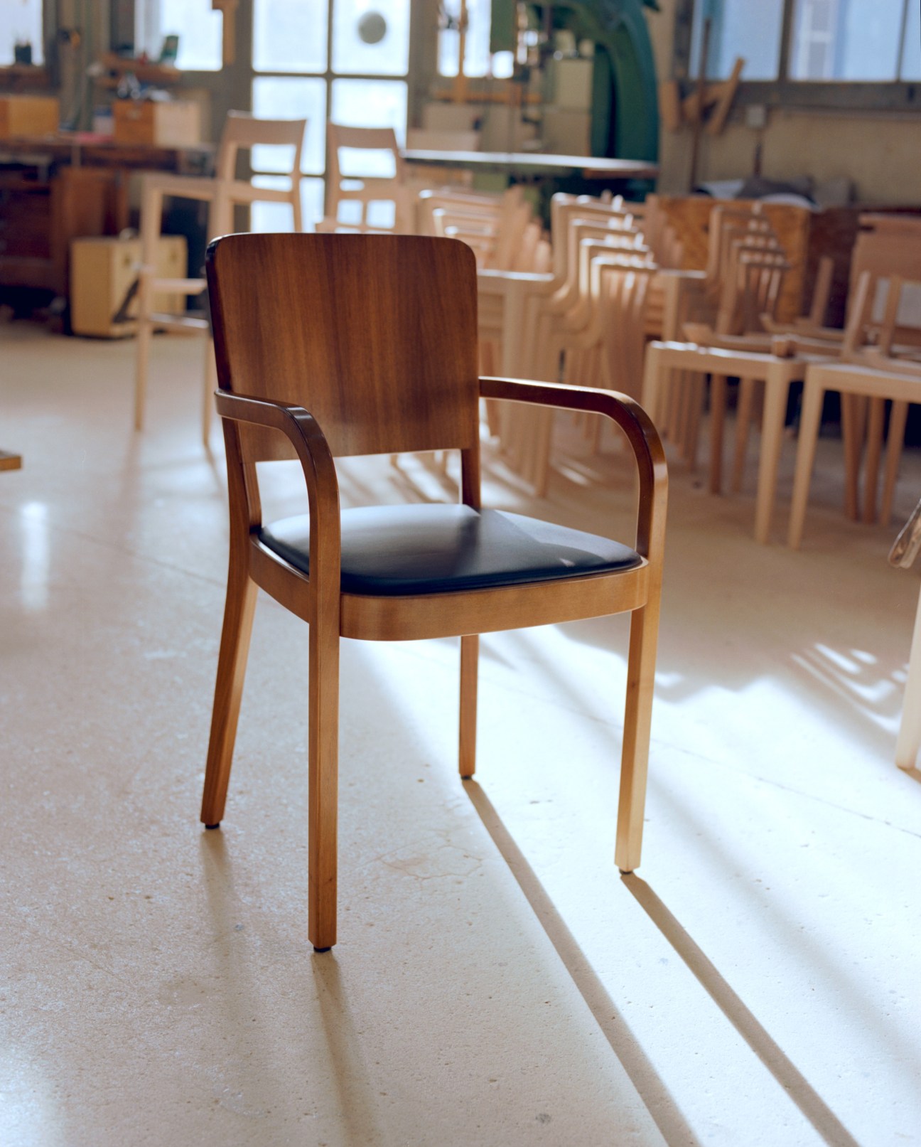 Horgenglarus Haefeli II wooden chair with dark leather seat in a factory showroom.