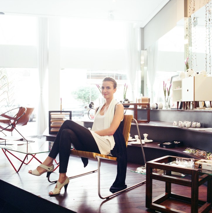 Architect Manoela Beneti sits in her minimalist design store Grampo, surrounded by curated home décor and furnishings.