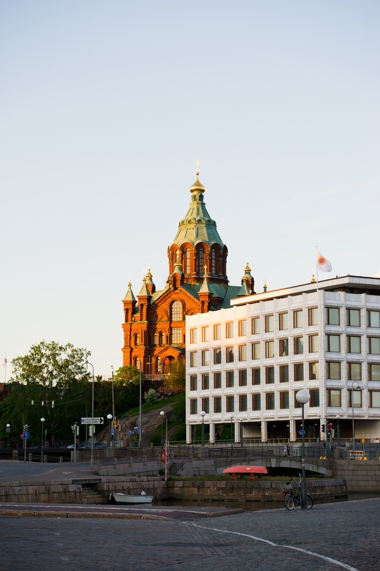 Orthodox cathedral with golden dome and ornate red-brick architecture beside modern white office building on waterfront