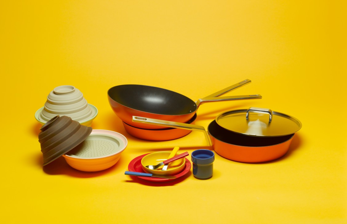 Colorful orange and cream tajine cooking pots and pastel dishware arranged on bright yellow background.