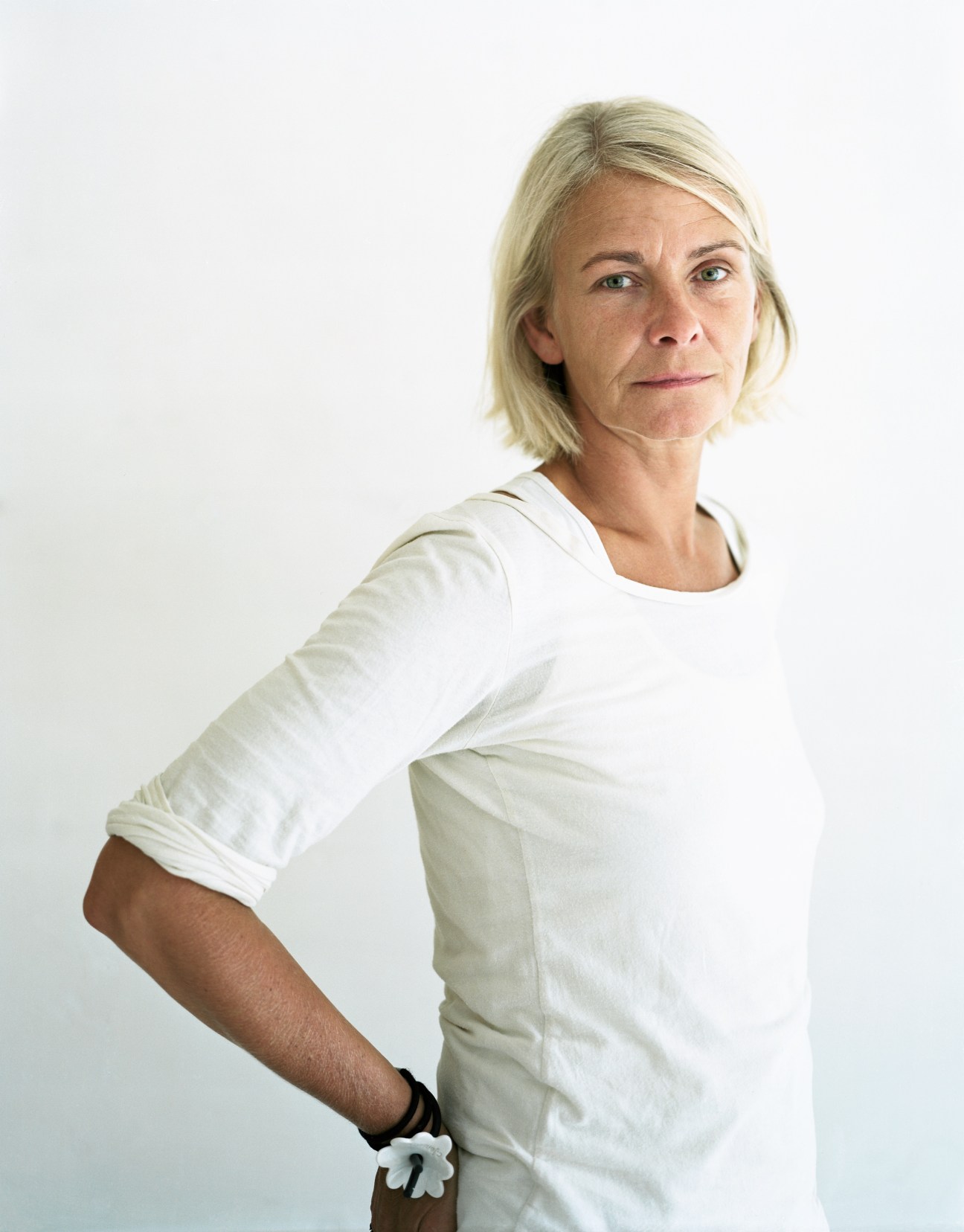 Woman with blonde hair in white t-shirt poses against white background.