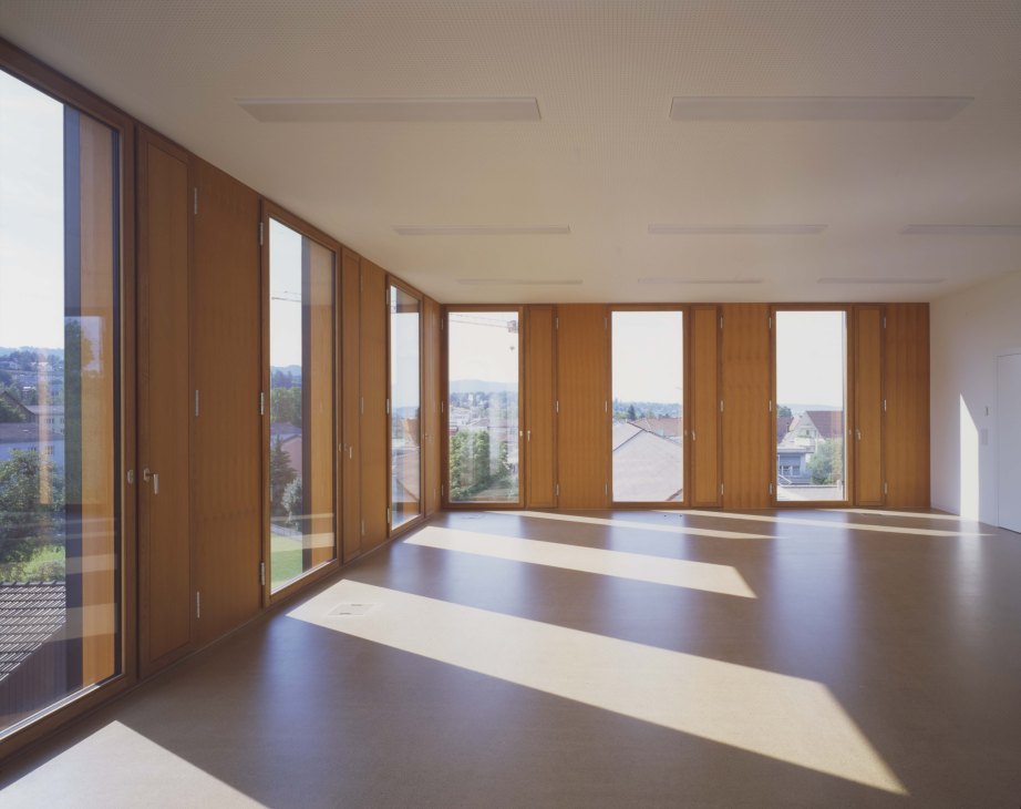 Bright classroom with wood-framed glass doors and windows overlooking a landscape.