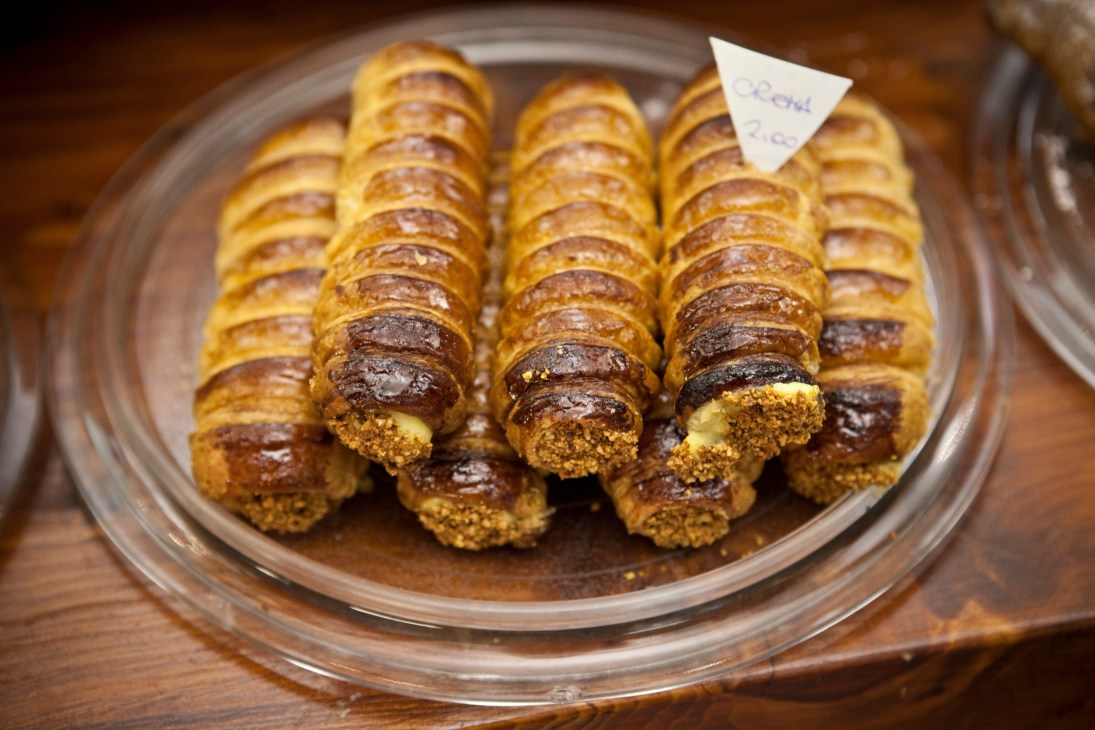 Cannoli pastries with chocolate coating and cream filling arranged on a plate with a price label.