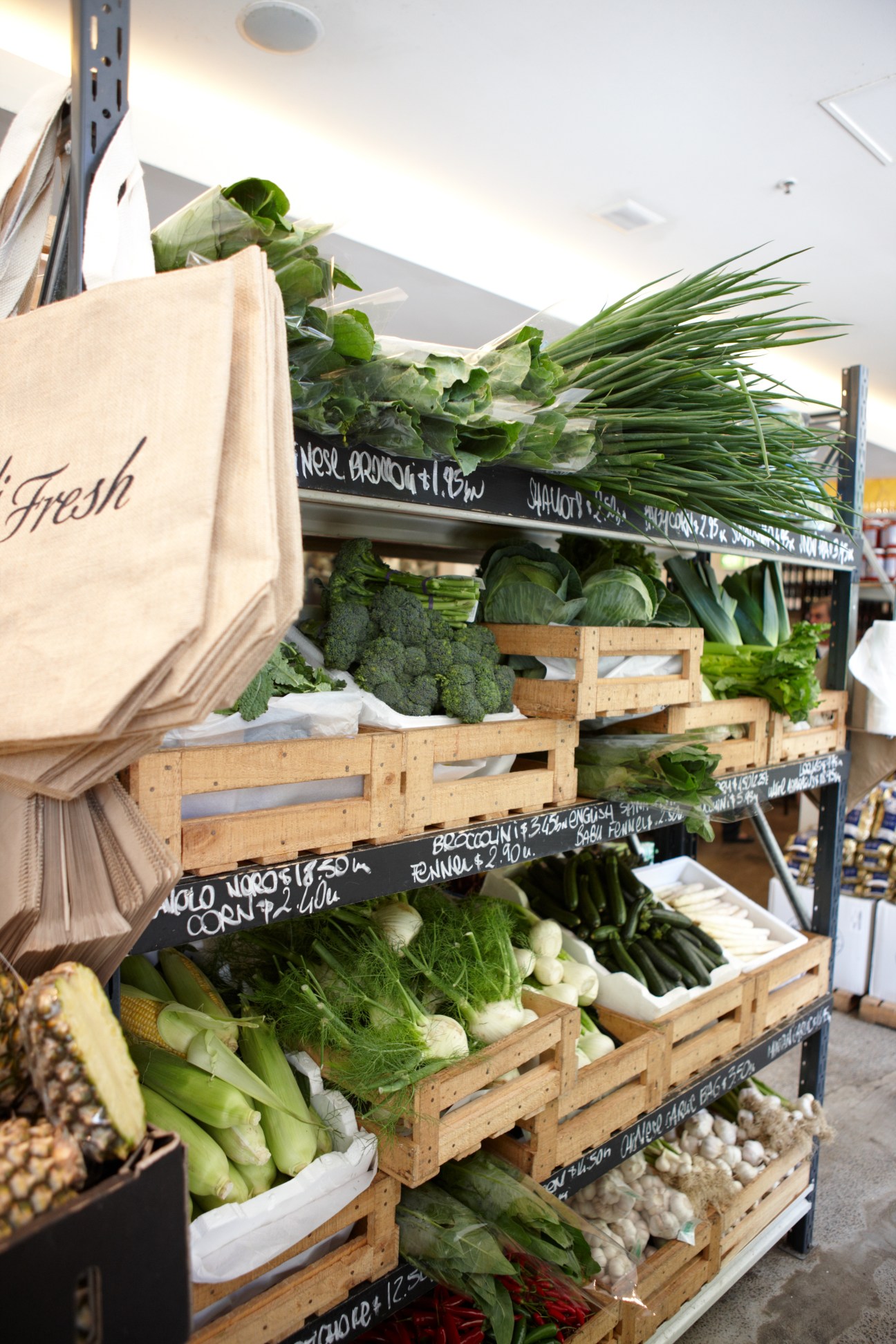 Wooden crates display fresh produce including broccoli, green onions, and leafy vegetables at Fratelli Fresh market.