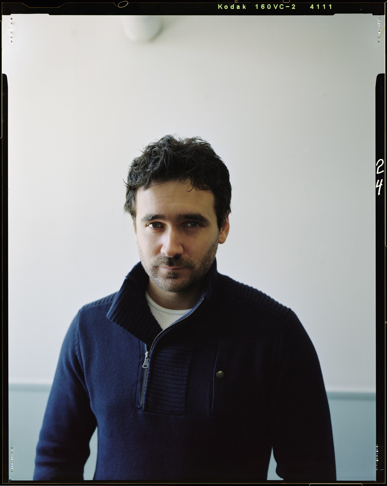 Portrait of Allan Hawco, creator and star of Republic of Doyle, wearing a dark blue sweater against a white background.