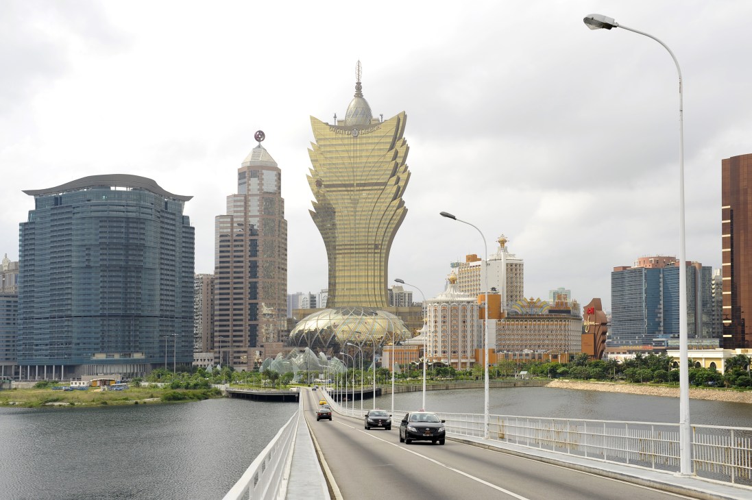 Macau's modern skyline featuring luxury casinos and high-rise buildings along a waterfront causeway.