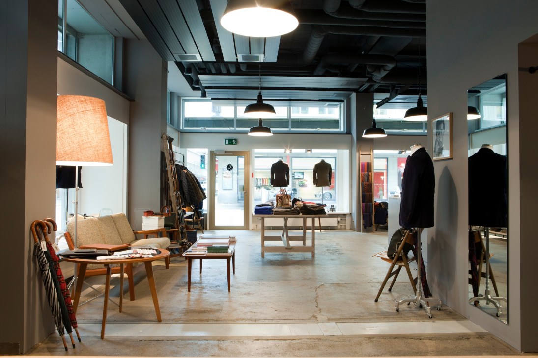 Modern retail interior of Pelikamo menswear store in Zürich with minimalist design, clothing displays, and mid-century furniture.