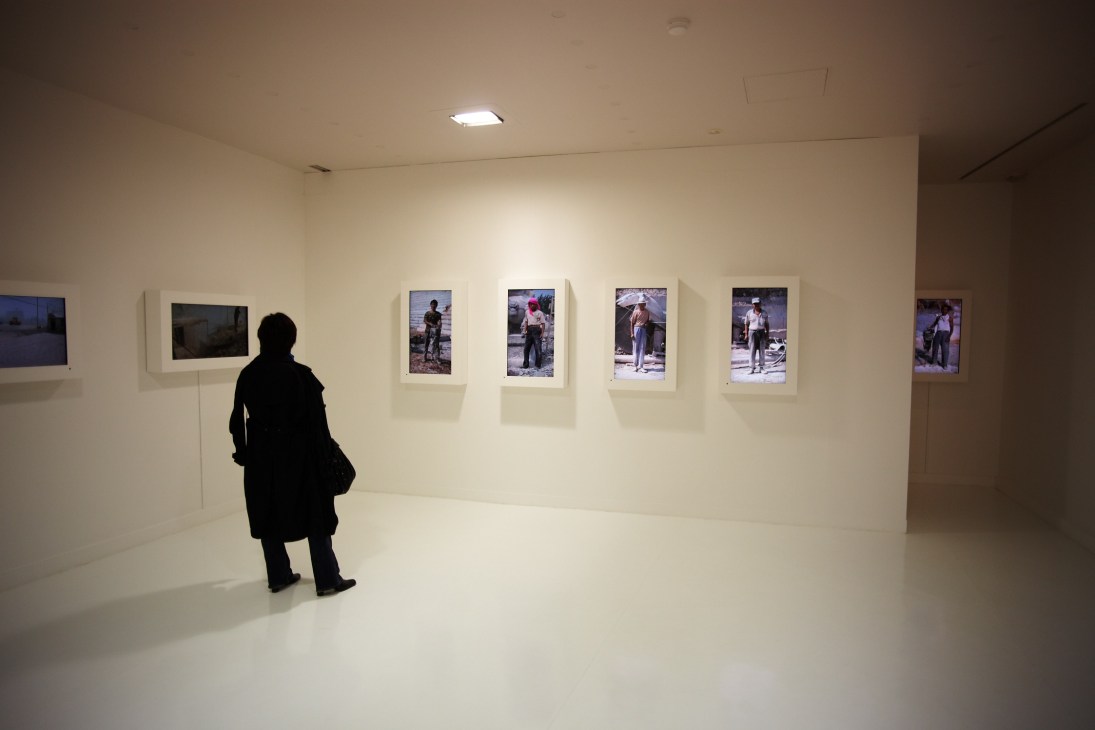 Visitor viewing photographs displayed on white gallery walls in a minimalist museum space.