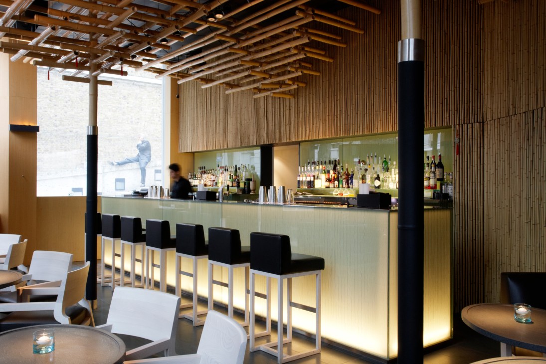 Interior of Saké no Hana restaurant showing minimalist bar counter with black stools and wooden ceiling details.