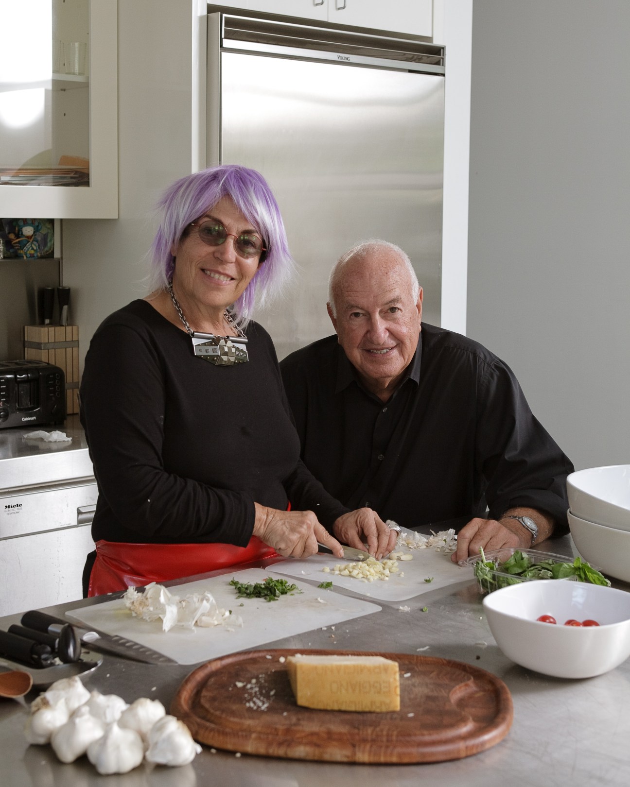 Mera and Don Rubell smile while preparing spaghetti alla Mera in their modern kitchen.
