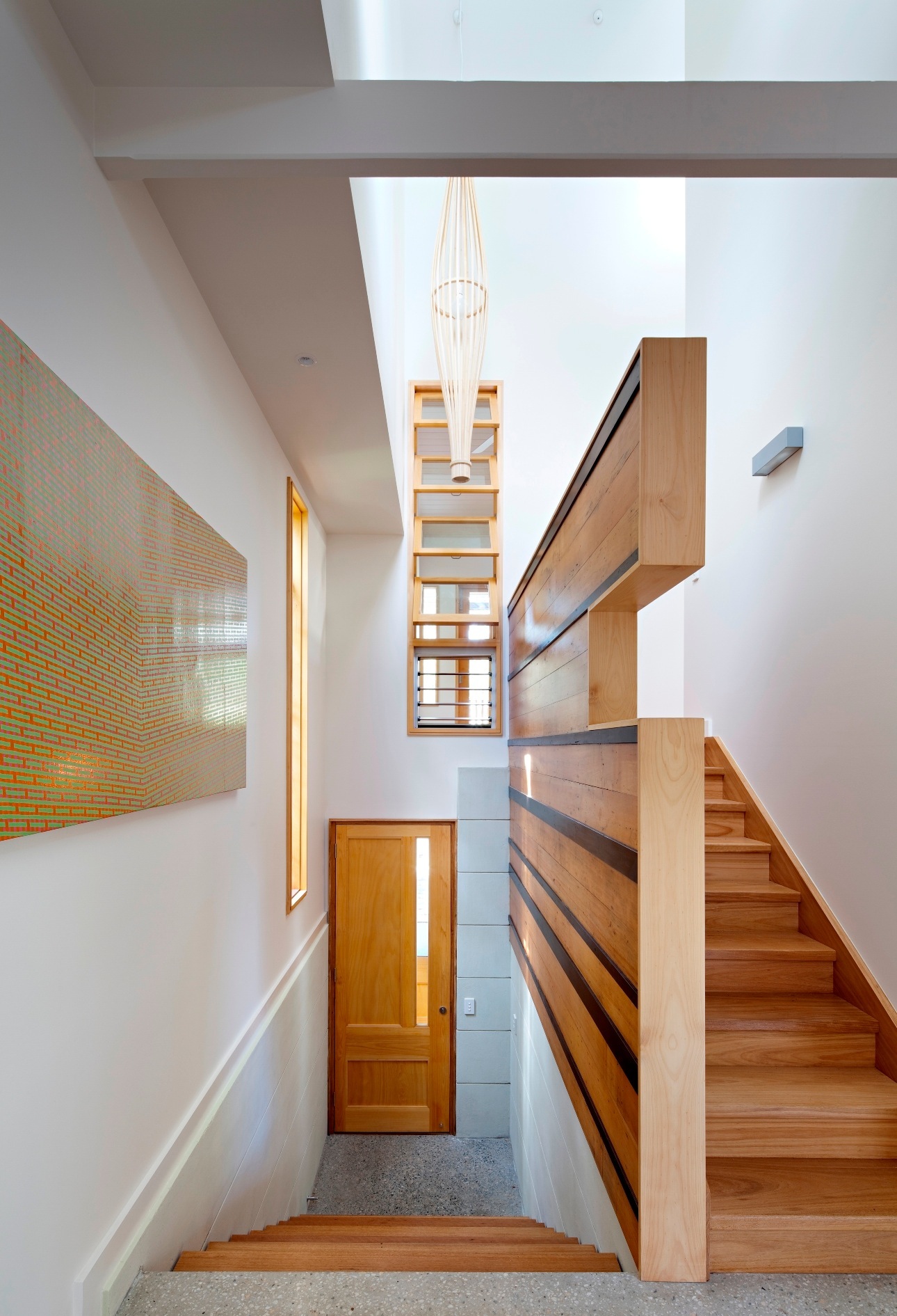 Bright stairwell with wooden steps, handrails and a pendant light fixture in a renovated Queensland residence.