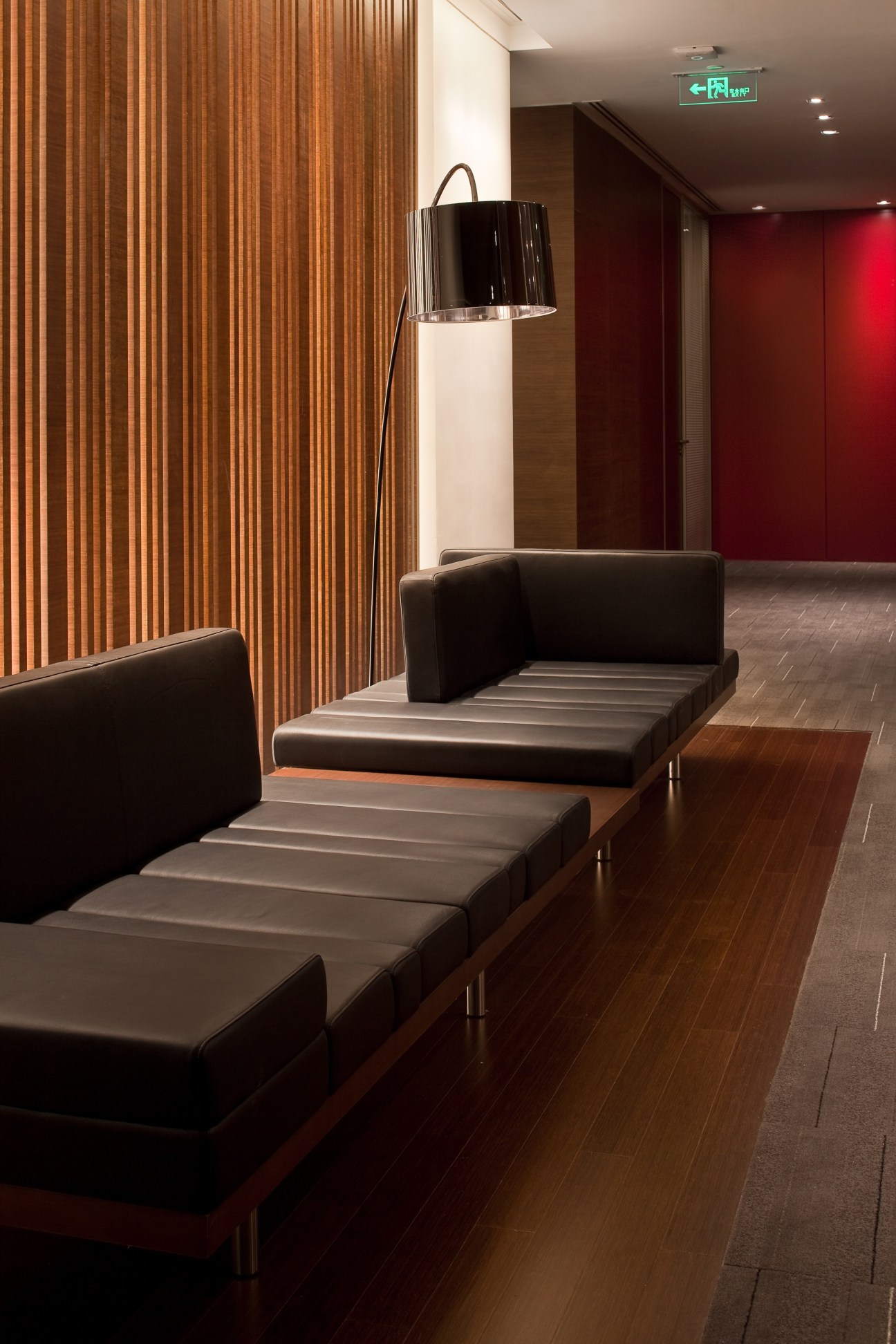 Modern corridor with wooden slat wall, black leather seating, and arc floor lamp in HSBC Shanghai office