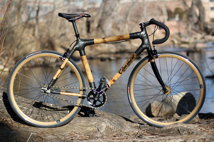 Bamboo bicycle with natural wood frame and black components against blurred waterside background.
