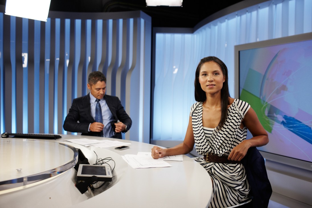 Janice Peterson sits at a news desk in an SBS studio, preparing to present World News.