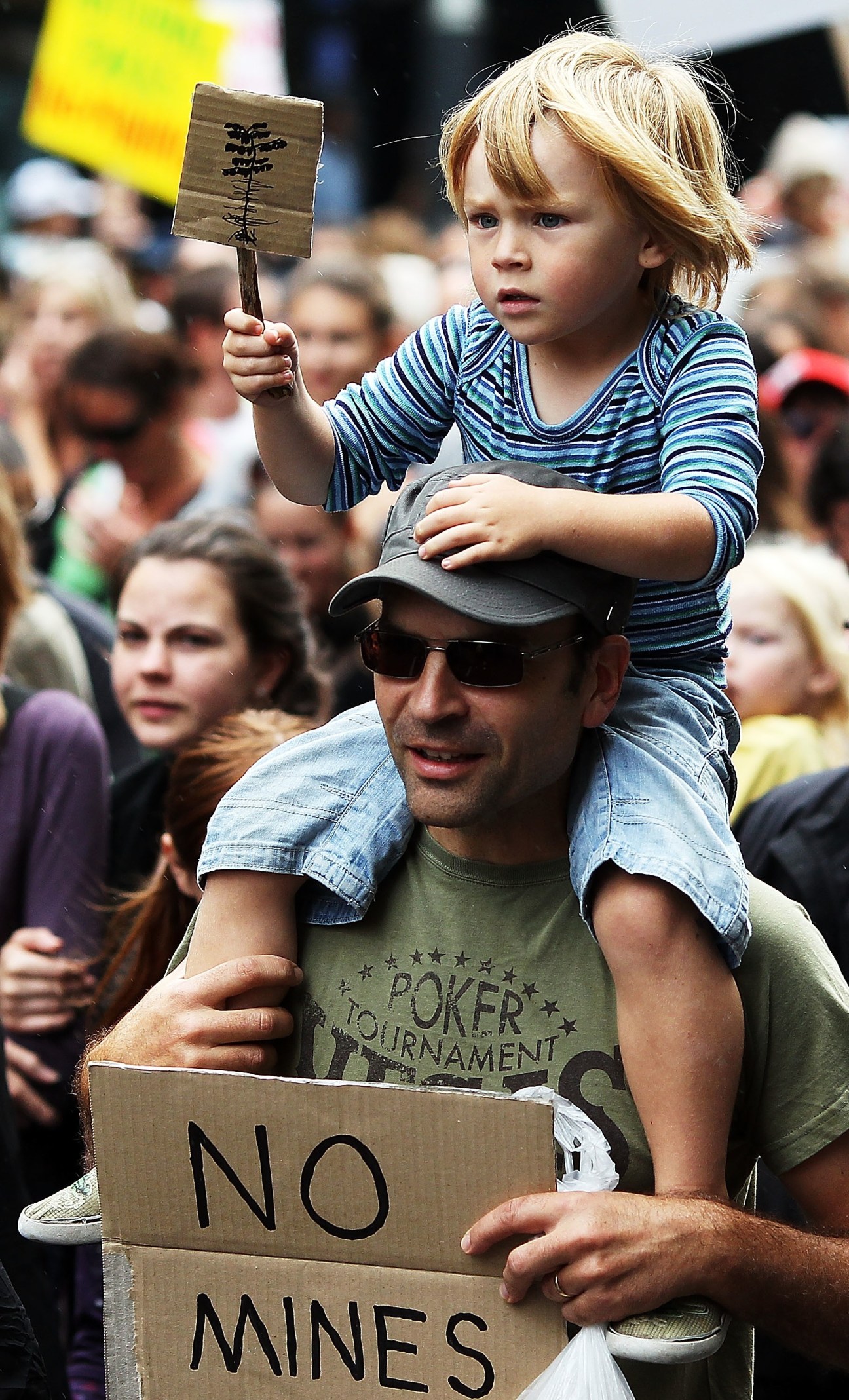 Child holding protest sign reading 'NO MINES' at anti-mining demonstration in Auckland, New Zealand.