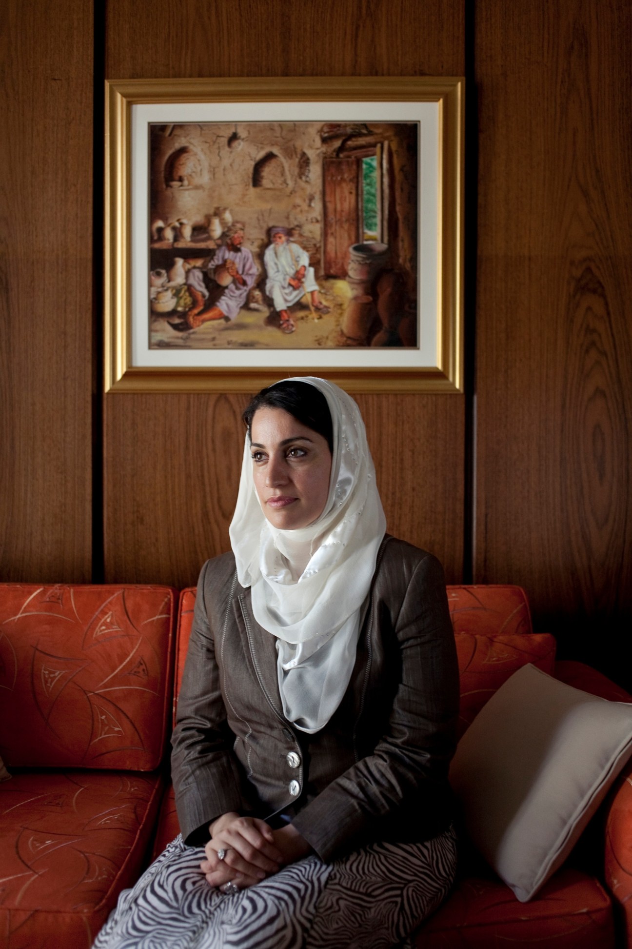 Dr Mona Fahad al Said, senior official at Sultan Qaboos University, seated on red sofa wearing hijab and business attire.