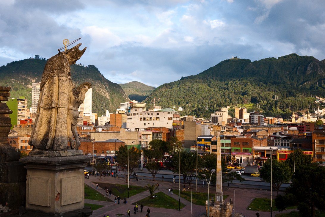 Gold statue of a bird overlooking Bogotá's Bronx neighbourhood with mountains in background.