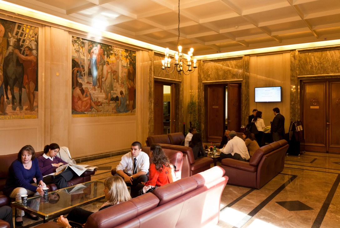 WTO building interior with staff in formal meeting lounge area with burgundy seating.