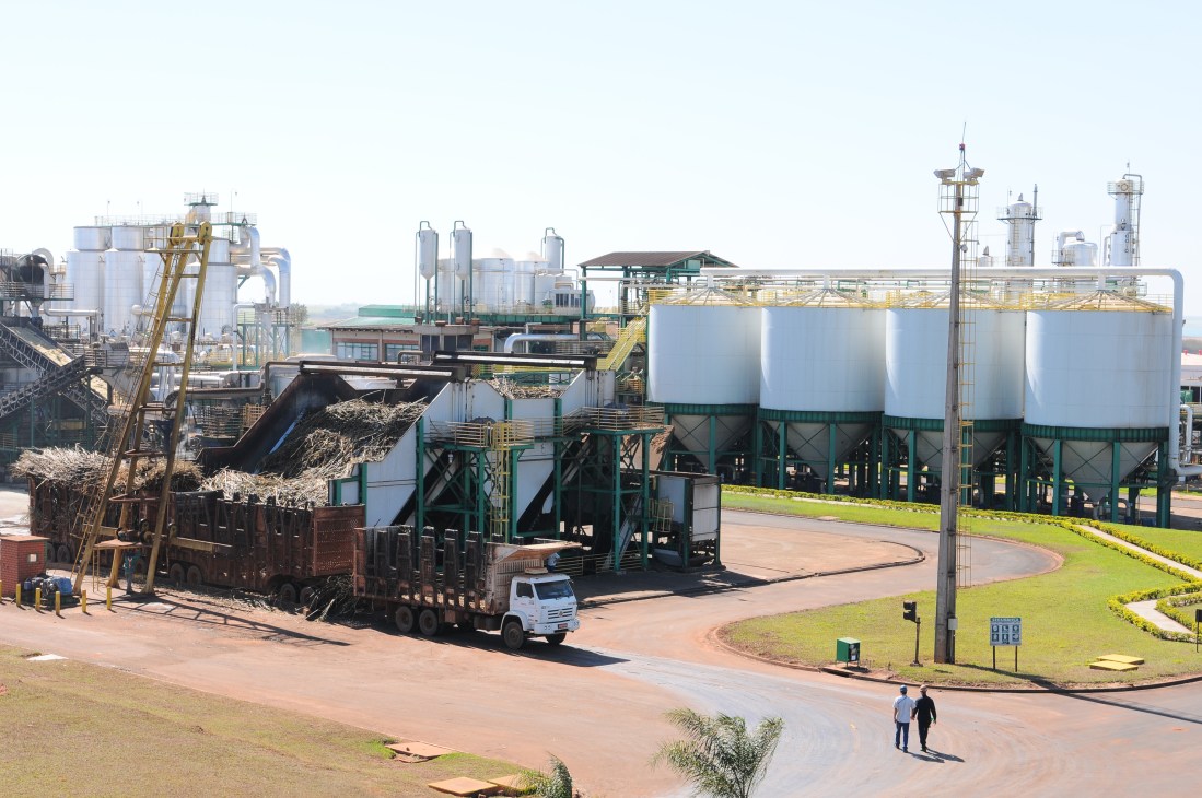 Industrial ethanol processing facility with large storage tanks, loading equipment, and transport truck in Brazil.
