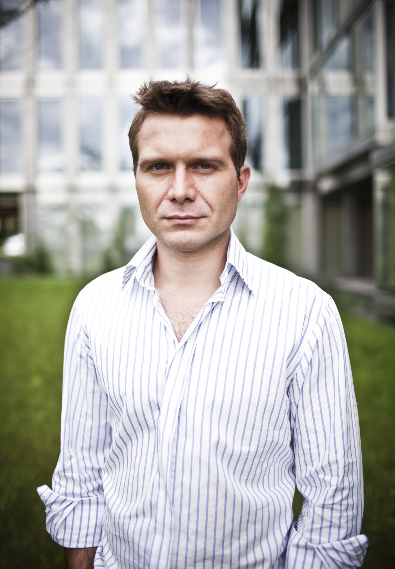 Portrait of Boguslaw Krysinski, vice-president of Debt Trading Partners, wearing a blue striped shirt in an urban courtyard setting.