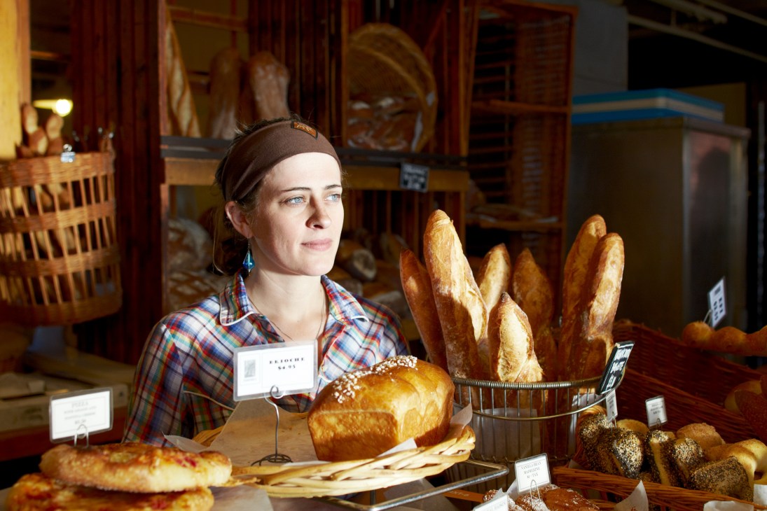 Woman at The Standard Baking Company counter with fresh bread and pastries on display