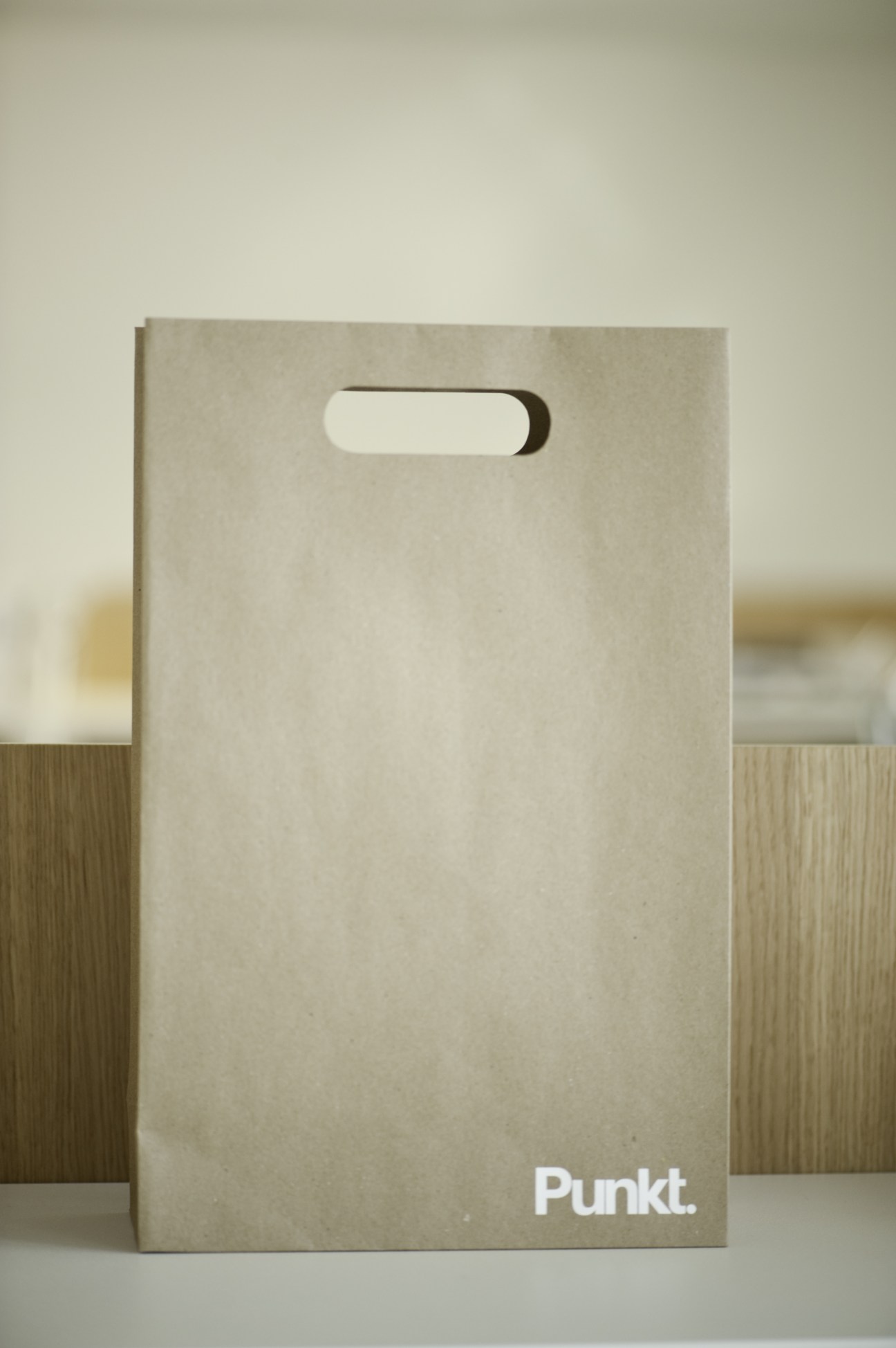 Minimalist kraft paper packaging box with die-cut handle and Punkt branding in white.