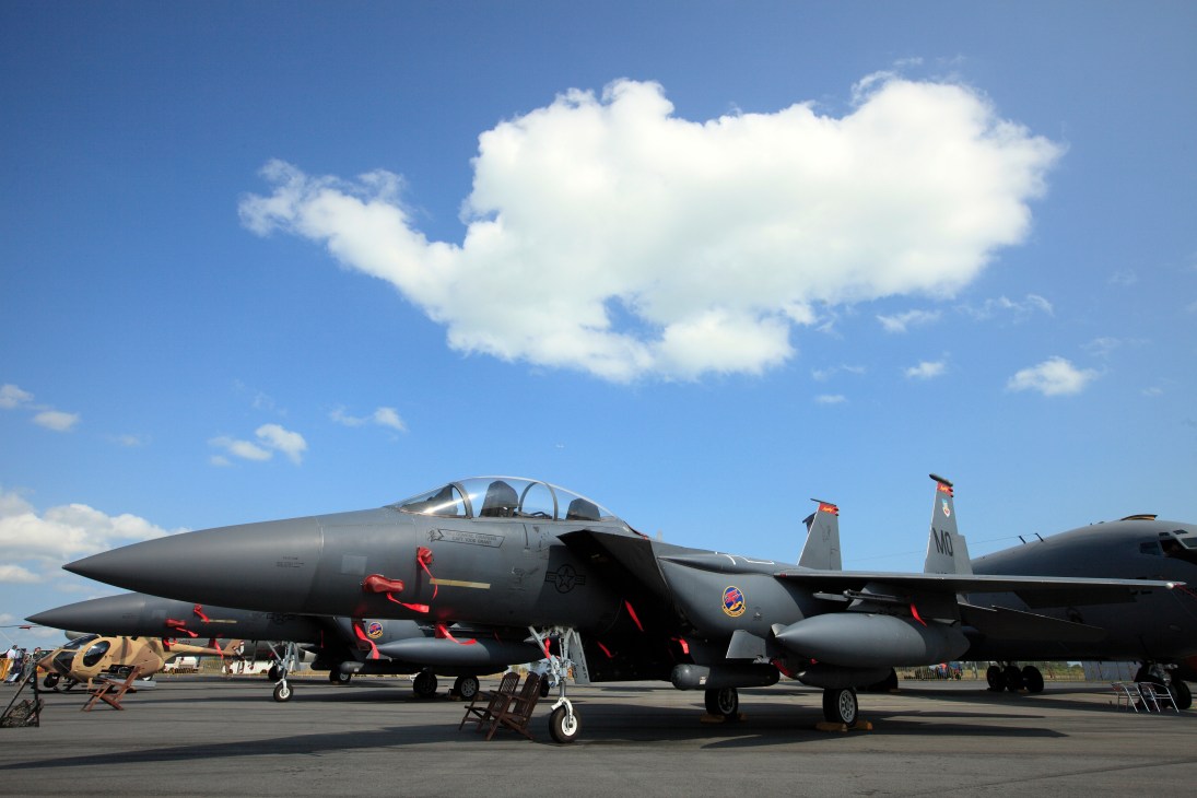 Two US Air Force Boeing F-15 Eagles fighter jets on display at Singapore Air Show with red ribbons attached.