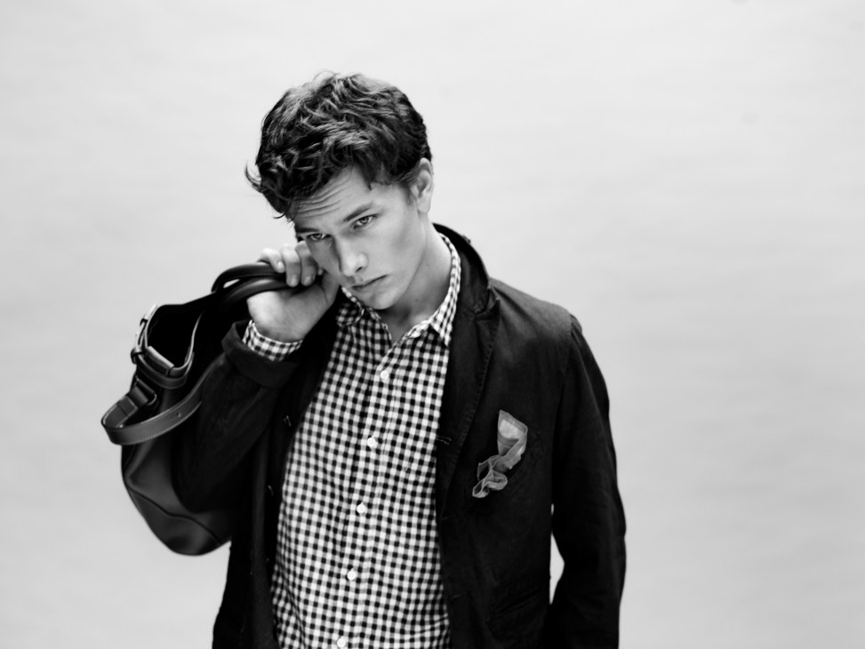 Man in Engineered Garments jacket and Beams+ gingham shirt holding Church's leather bag.