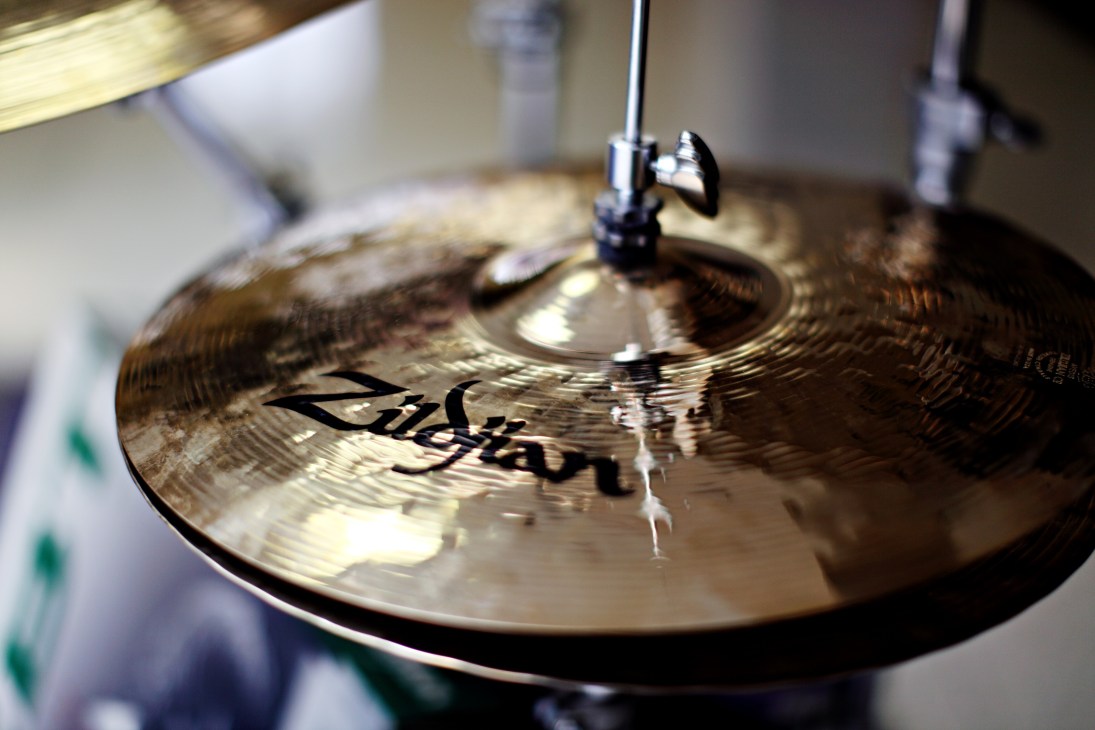 Close-up of a Zildjian cymbal with drumstick mid-strike showing the brand logo and textured surface.