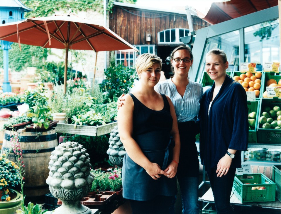 Three smiling women staff members standing in the garden of Mutter Fourage deli/cafe