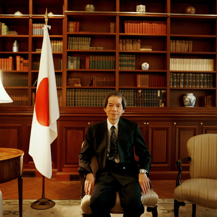 Tsuneo Nishida, Japan's permanent representative to the UN, seated in a formal office with Japanese flag and bookshelves.
