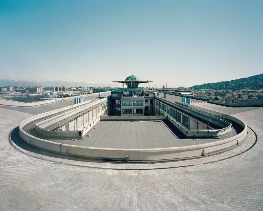Aerial view of the circular test track atop the Lingotto Fiat factory with Turin's cityscape and Alps in the background.