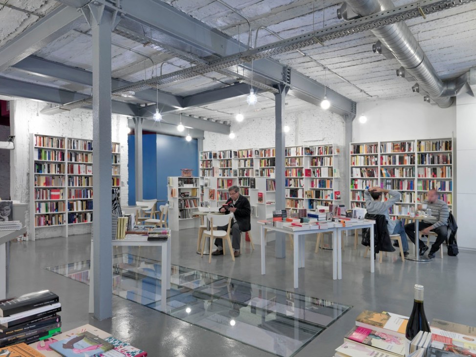 Interior of Tipos Infames bookshop in Madrid with shelves of books, tables, and visitors browsing.