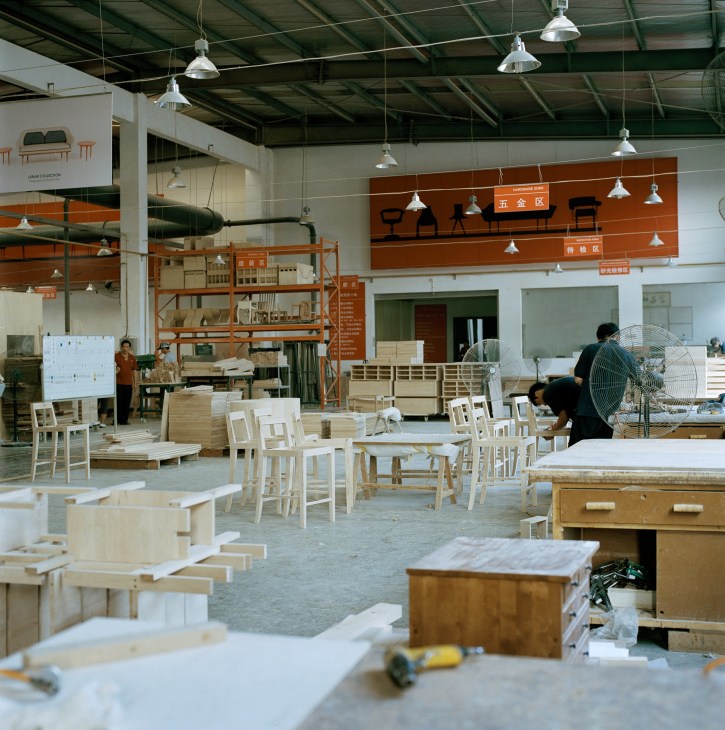 Furniture Labo factory interior showing wooden chairs and tables in various stages of production with workers at assembly stations.
