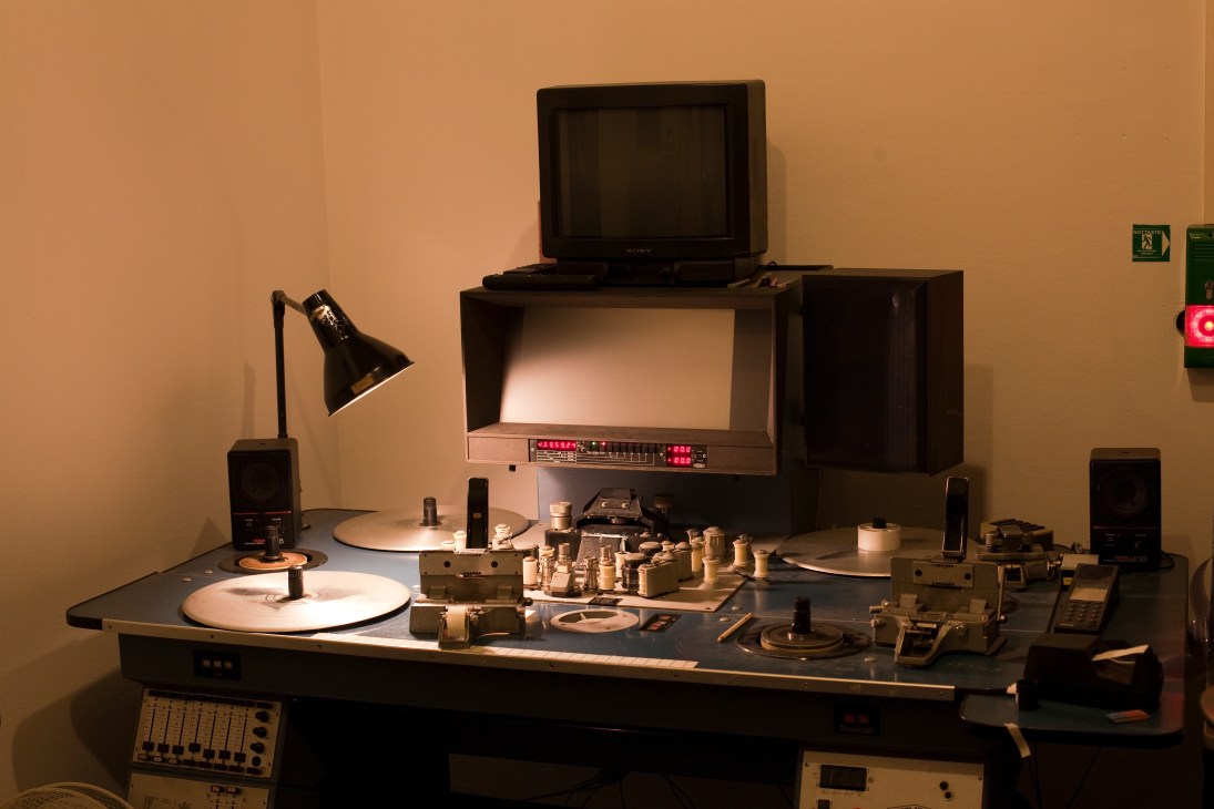 Vintage dubbing equipment including tape decks, monitor, control panel and lamp on desk in Berlin studio.