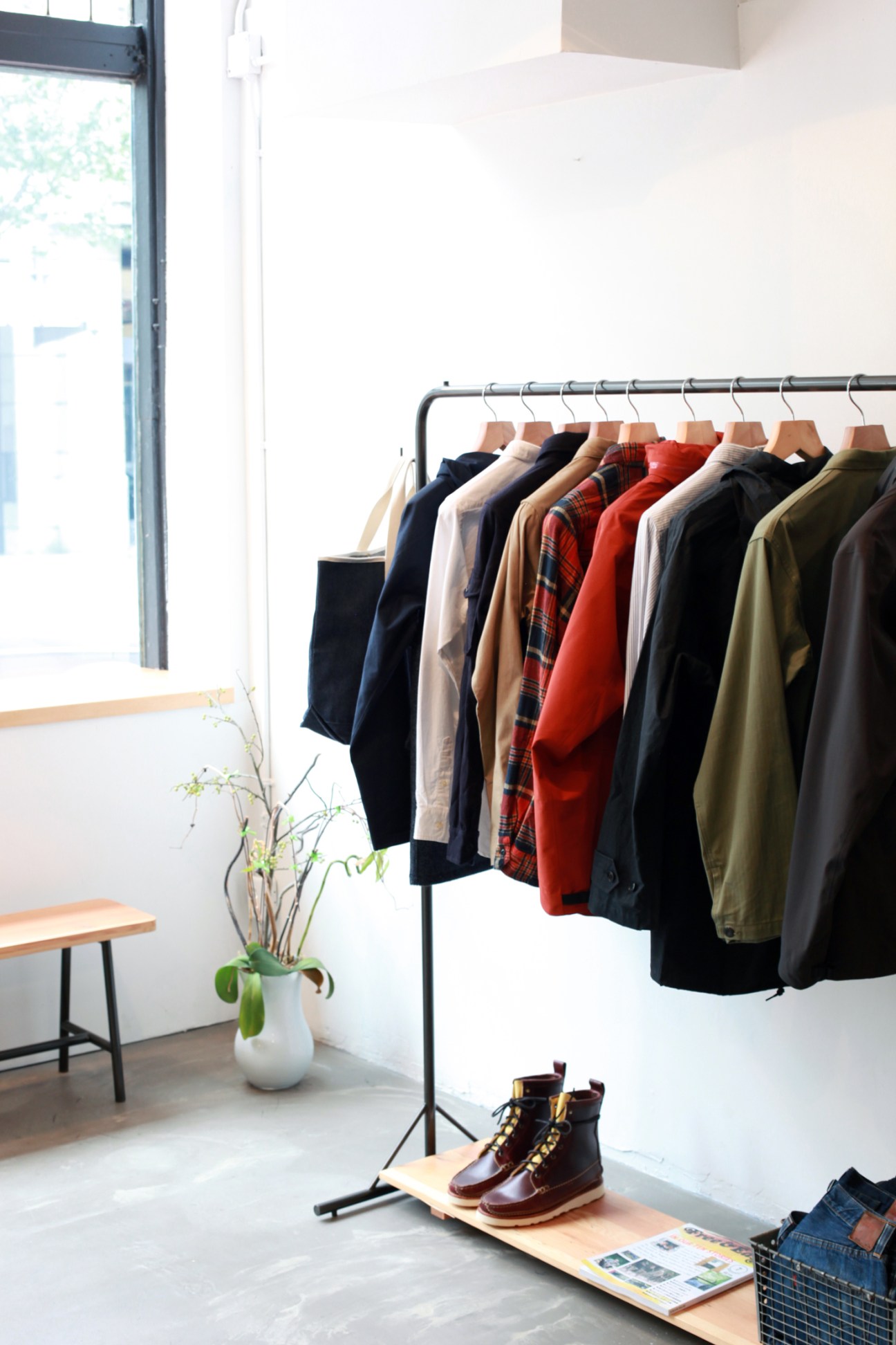 Inventory store interior in Vancouver displaying clothing on a rack with a white vase and boots on display.