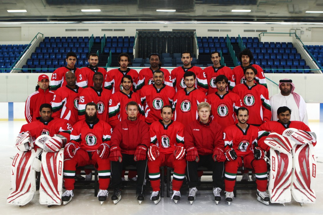 UAE national ice hockey team in red uniforms poses for a group photo on the rink.