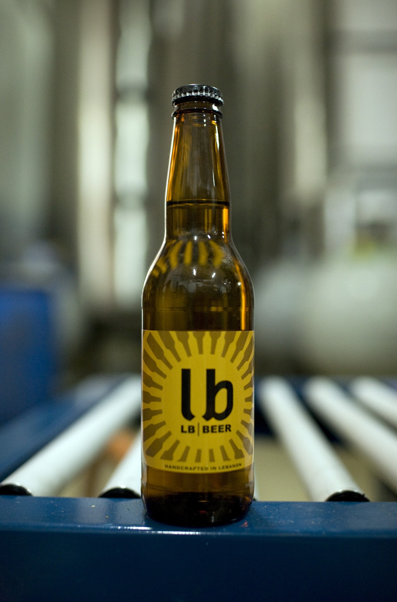 LB Beer bottle with yellow label featuring a sun symbol and "lb|BEER" text, labeled "Handcrafted in Lebanon".