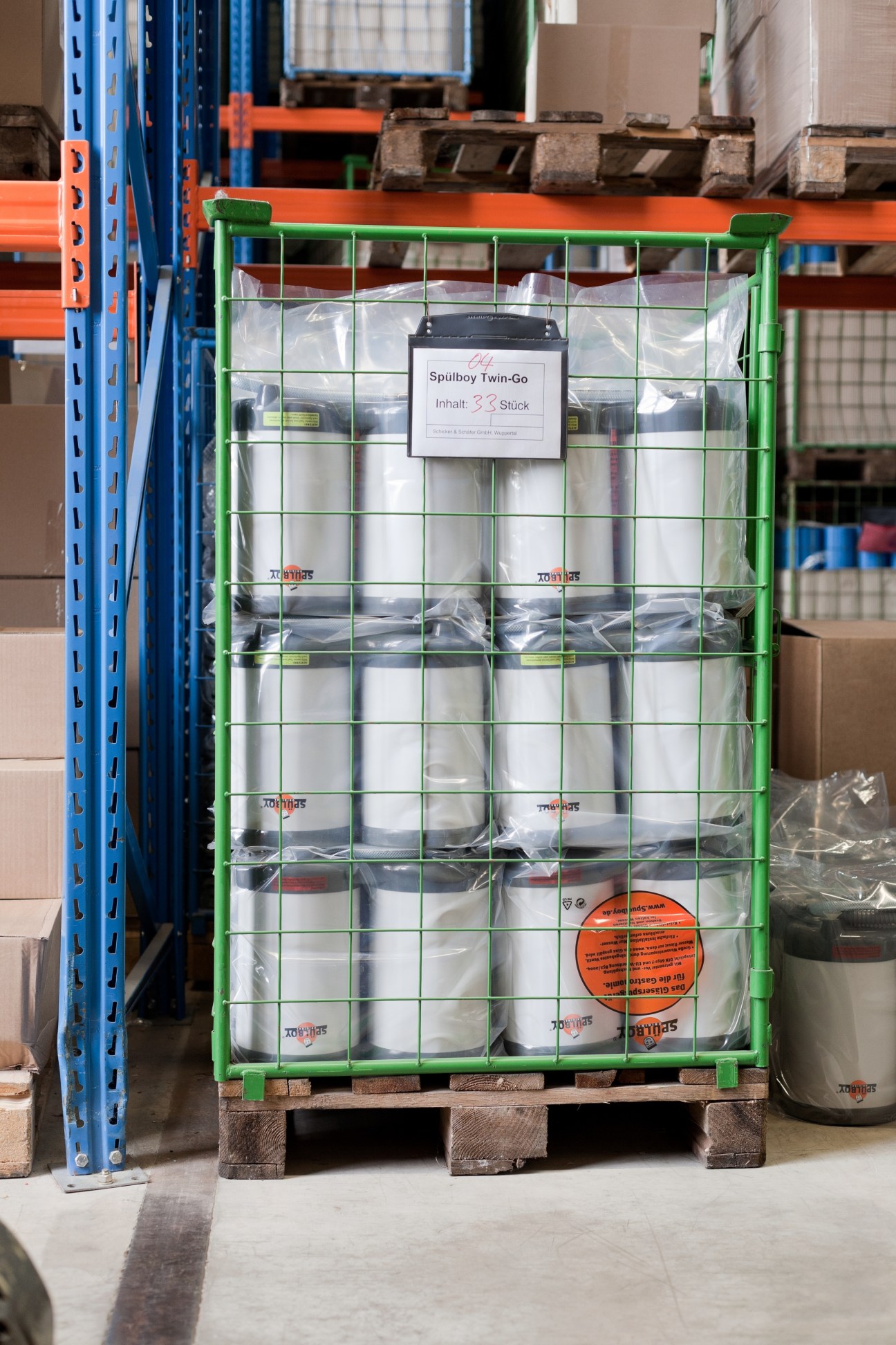 Green metal crate of packaged Spülboy Twin-Go glass washers in a factory warehouse.