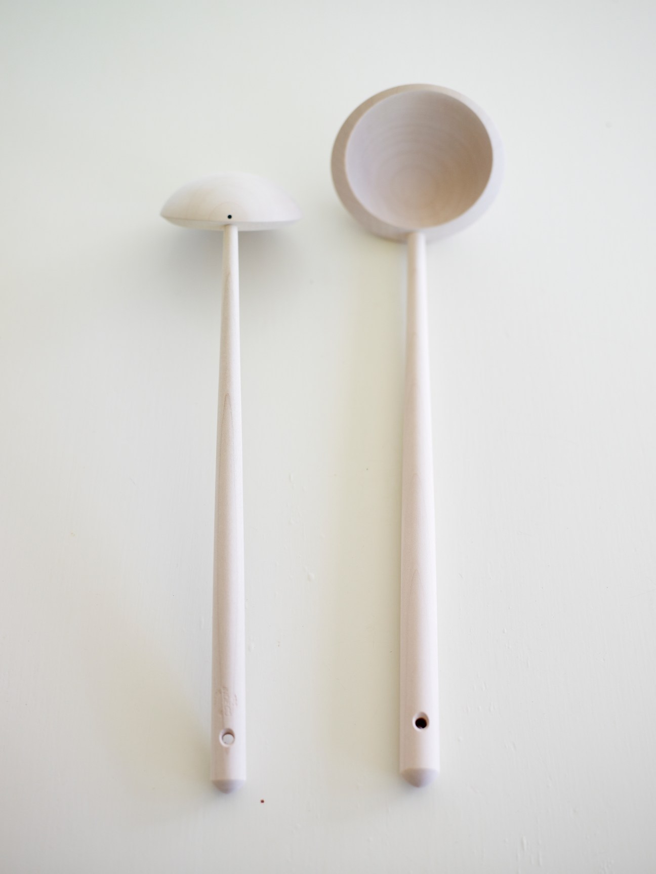 Two wooden ladles with long handles and round bowls against a white background.
