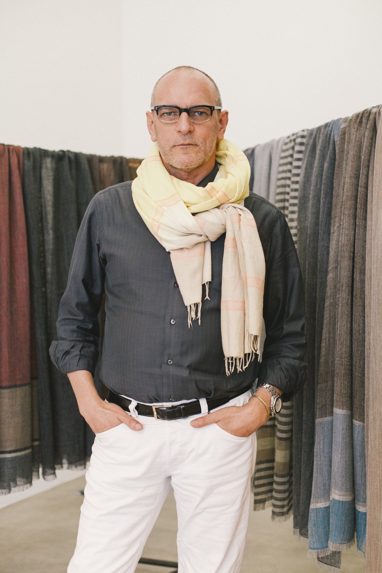 Arnold Haas, founder of Wubet scarf brand, posing in front of displayed textiles