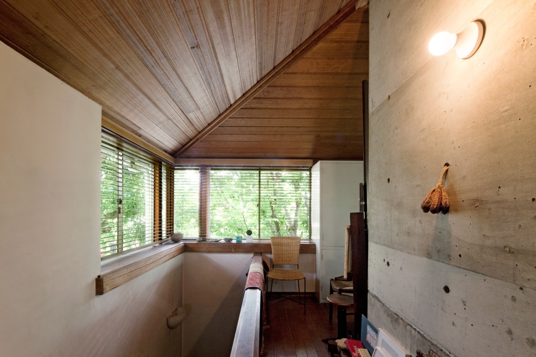 Interior corner showing wood-planked ceiling and concrete walls with natural light filtering through horizontal blinds