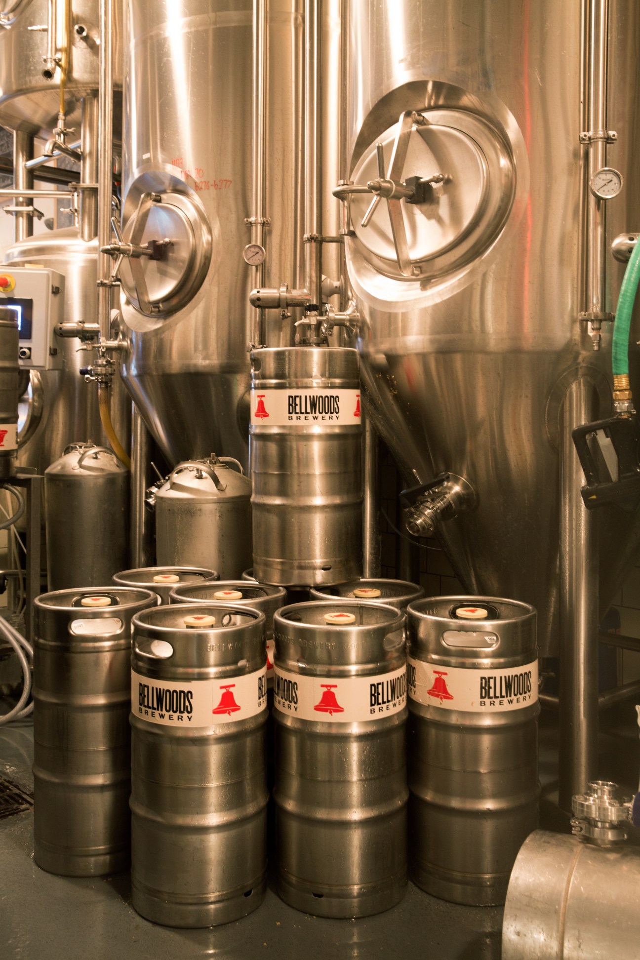 Stainless steel brewing tanks and Bellwoods Brewery kegs in a brewery facility.