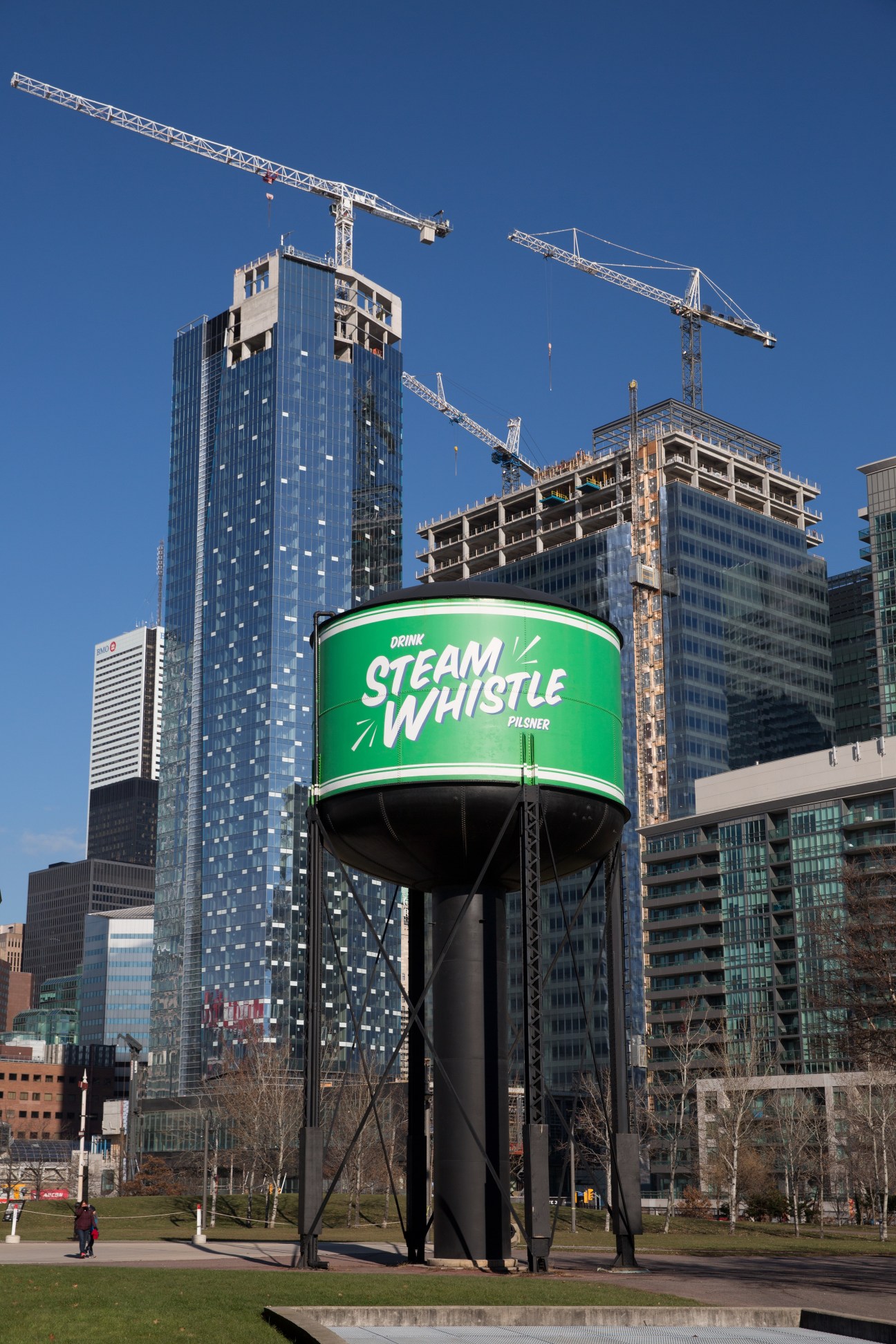 Steam Whistle Pilsner water tower advertisement among downtown Toronto skyscrapers and construction cranes.