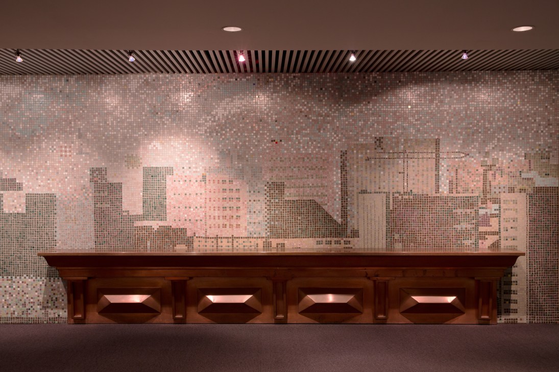 Pixelated mosaic mural of Toronto skyline above wooden seating in City Hall interior.