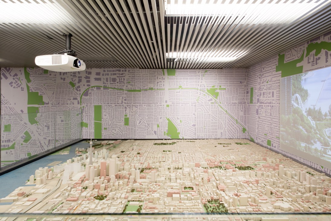 Scale model of Toronto displayed in a modern gallery space with map wallpaper and linear ceiling design.